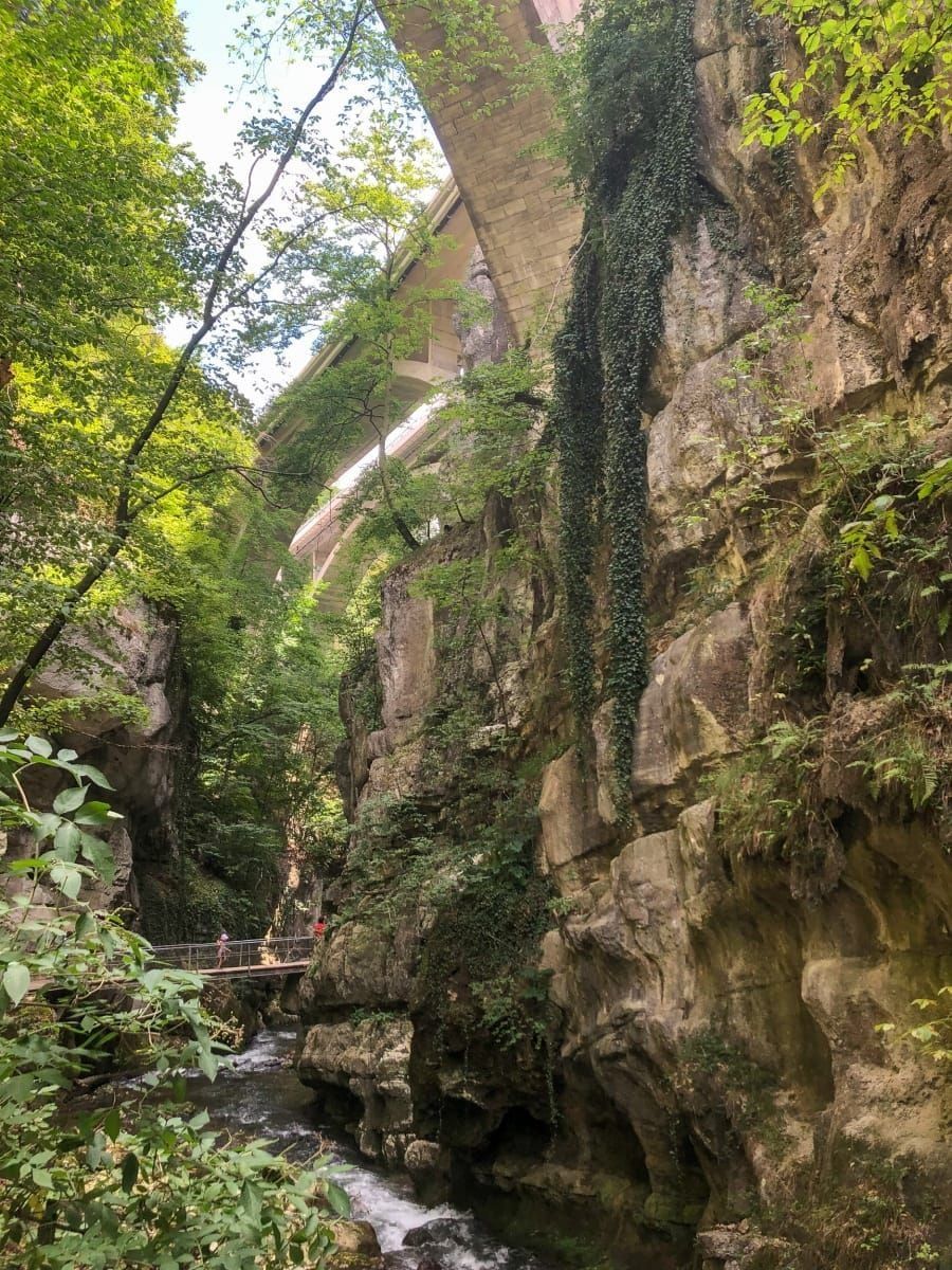 Steg mit Geländer und Brücke über der Schüss in der Taubenlochschlucht